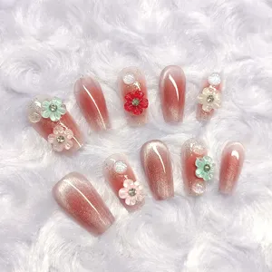 Detalle en primer plano de uñas postizas artesanales efecto ojo de gato con flores 3D.