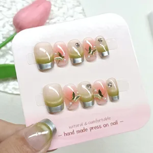 Uñas postizas hechas a mano con degradado cat-eye, puntas french plateadas y mariposas doradas.