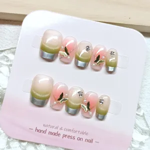Primer plano detallado de uñas postizas hechas a mano con efecto ojo de gato y mariposas.