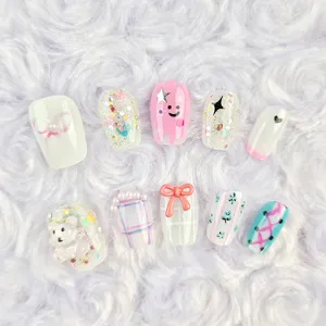 Primer plano detallado de uñas postizas con bonitos diseños de ositos y lazos en 3D.