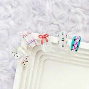Detalle de uñas postizas hechas a mano con lazos 3D, ositos lindos y diseños de cuadros.