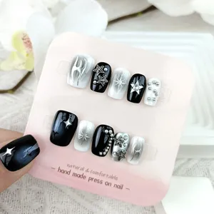Primer plano de uñas postizas artesanales estilo Y2K adornadas con estrellas metálicas.