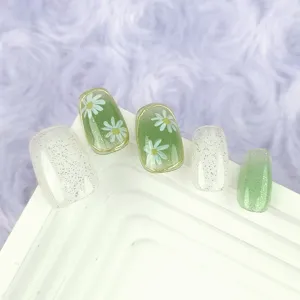 Uñas postizas hechas a mano con frescos diseños florales verdes y detalles brillantes.