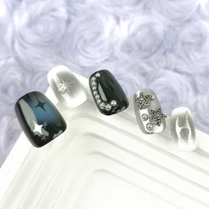 Detalle de uñas postizas plateadas Y2K con estrellas metálicas y tachuelas decorativas.