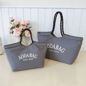 Grijs canvas tote bag met touw handvatten en letterprint, ideaal voor dagelijks gebruik.