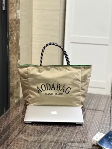 Casual beige canvas tote bag with black and white rope handles and green inner lining.