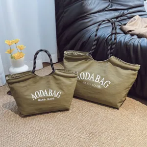 Gedetailleerd overzicht van de grote canvas shopper in olijfgroen met motief handvatten.