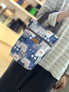 Close-up detail of cute cat print canvas tote bag with front zipper pocket and handle.