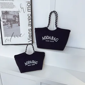 Minimalistische zwarte canvas shopper met touw handgrepen, grote dagelijkse tas.