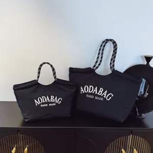 Gedetailleerd overzicht van zwarte canvas tote tasjes met stijlvolle print en handvat.