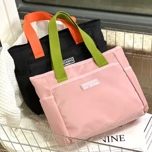 Details of the color-block canvas tote bag featuring contrast handles and front pocket storage.