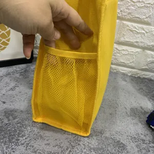 Detalle de primer plano del bolso de lona amarillo que muestra el bolsillo de malla lateral.