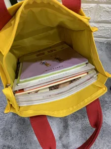 Detalle del interior del bolso de lona que muestra varios libros guardados ordenadamente.