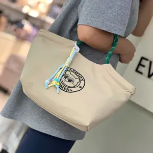 Detailed view of the stylish waterproof lunch handbag with cute bear logo and colorful charm.