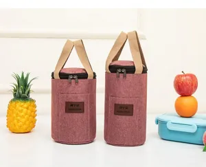 Detail shot of cylindrical insulated bento bag with pink waterproof fabric and beige handles.