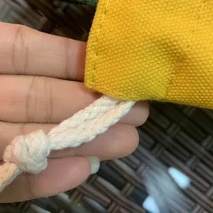 Vue rapprochée détaillée du sac à cordon en toile jaune avec une texture de corde tressée.