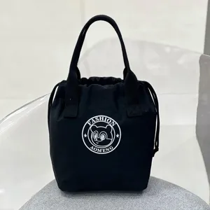 Detailed close-up view of the black canvas drawstring lunch bag, featuring sturdy dual handles.