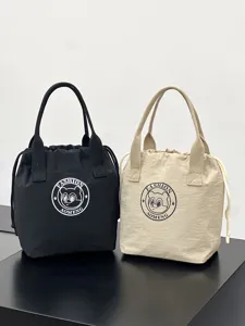 Detail view of canvas drawstring lunch tote bags in black and beige with cute round printed badge.