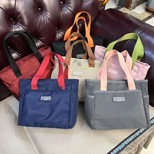 Detailed view showcasing multiple colored nylon handbag designs with dual handles for commuting.