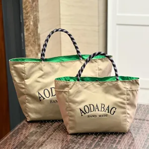 Detailed shot of large capacity khaki canvas tote bag with green inner lining and patterned handle.