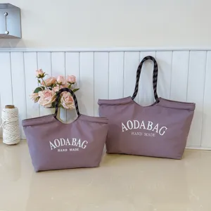 Gedetailleerd overzicht van grote canvas tote tas met touw handvatten en chique letterprint.
