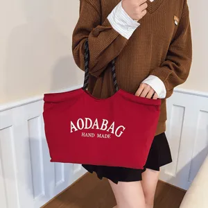 Grote rode canvas tote tas met zwart-witte handvatten en stijlvolle bedrukte letterdetails.