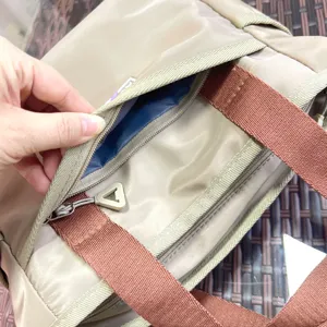Close-up detail of the handbag zipper pocket, showing blue lining and brown strap design.