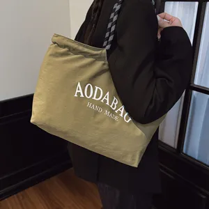 Gedetailleerd overzicht van khaki canvas tote bag, met letterprint voor dagelijks gebruik.