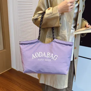 Gedetailleerd overzicht van de paarse canvas shopper met witte letters en dubbele handgrepen.