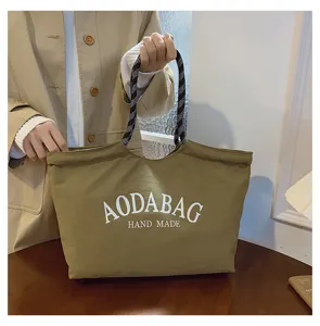Detailgezicht op de casual kaki canvas tote-tas met geprofileerde handvatten en duidelijke tekst.