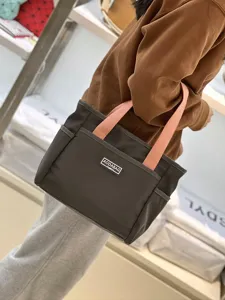 Detail view of casual two-tone canvas tote bag with front pocket and pink handles for daily use.