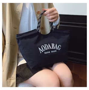 Zwarte casual canvas tote bag met contrasterend handvat en witte letters voor dagelijks.