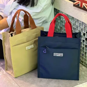Insulated lunch bag tote with contrast color handle and front pocket for daily use.