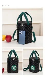 Cylindrical insulated lunch bag detail view, black geometric pattern with green straps.