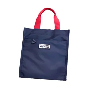 Color-blocked tote lunch bag with red handles and front zipper pocket, durable daily student bag.