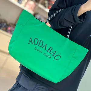 Close-up detail of the vibrant green canvas tote bag with contrast rope handles.