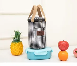 Detail view of portable insulated houndstooth bento bag with beige canvas handles and zipper.