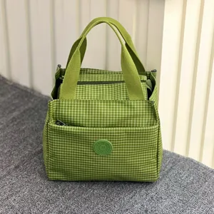 Gedetailleerd overzicht van de groen geruite lunchtas met handige handgrepen.