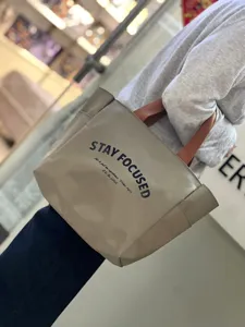 Detail shot of a minimalist two-tone oxford lunch bag with sturdy brown handles and bold text print.