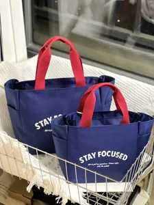 Detailed shot of large capacity oxford cloth lunch bag with contrast red handles and pockets.