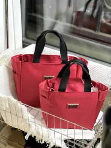 Detail view of the red canvas lunch tote bags inside a metal basket with golden tag.