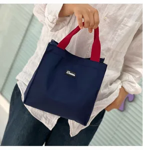 Minimalist color-block lunch bag, large capacity, durable fabric, with red handles for daily work.