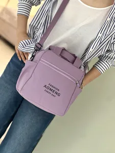 Detailed view of purple canvas crossbody lunch bag with dual handles and front zipper pocket.