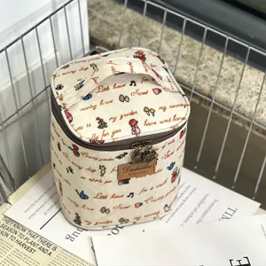 Cylindrical cosmetic bag and lunch tote with cute doodle print and handle for daily use.