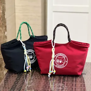 Detailed view of stylish canvas lunch handbag with rope handle and cute cartoon round logo design.