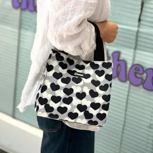 Detail view of the black and white heart pattern canvas lunch tote bag with handles.