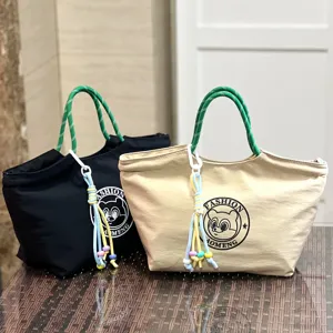 Close-up detail of waterproof lunch tote bag with green rope handle and cute bear logo.