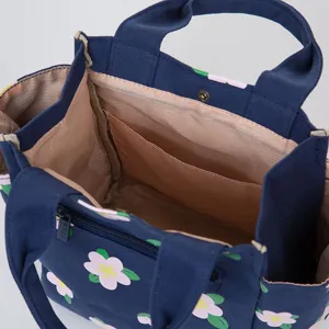 Blue canvas lunch bag with pink floral print, cute bento handbag for women and students.