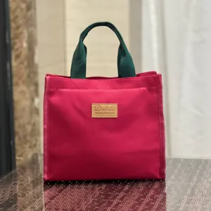 Borsa per pranzo in tela con manici verdi e corpo rosso, grande borsa bento portatile.