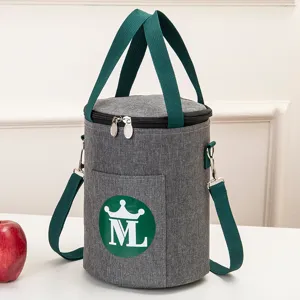 Cylindrical insulated lunch bag with green handles and shoulder strap, gray daily meal tote.